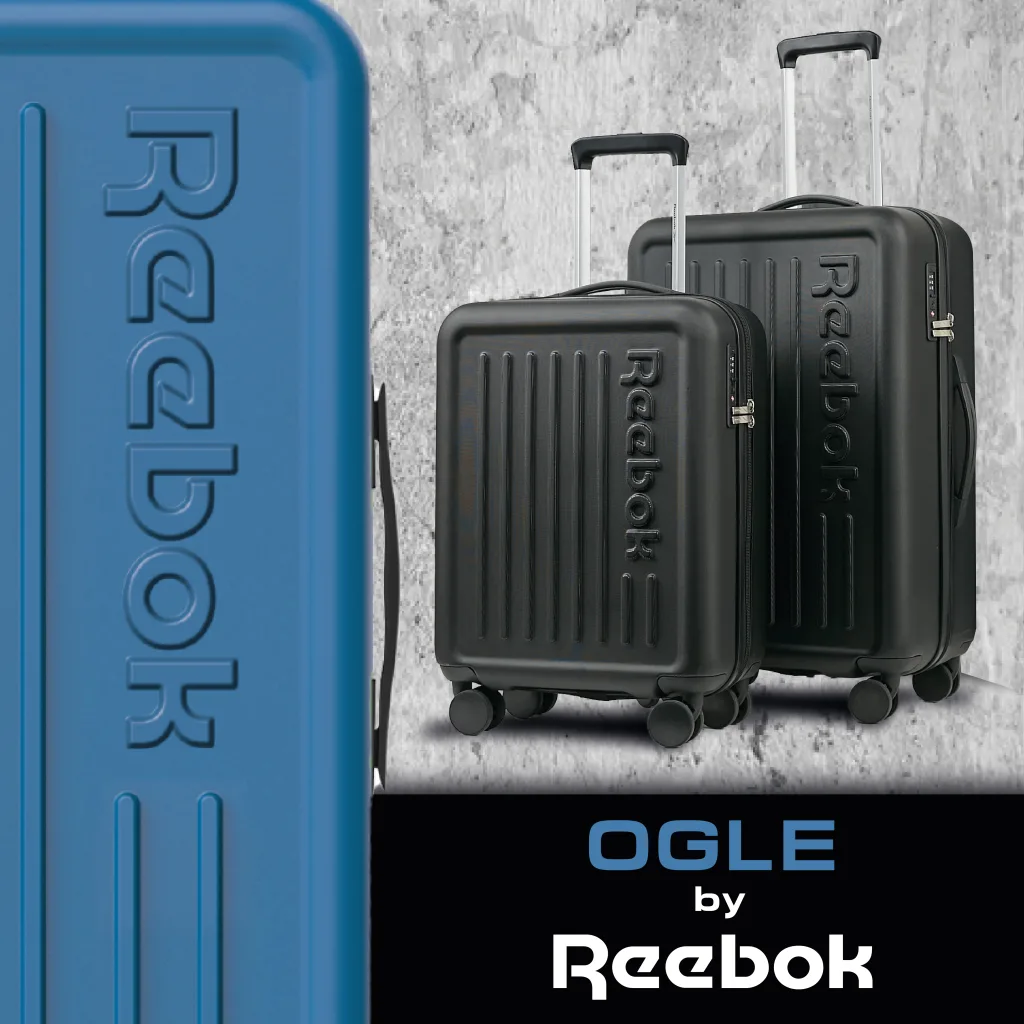 FCSI | Image of two black Reebok rolling suitcases with telescopic handles against a concrete backdrop. A blue vertical panel with the Reebok logo is on the left. The text "OGLE by Reebok" is at the bottom of the image.