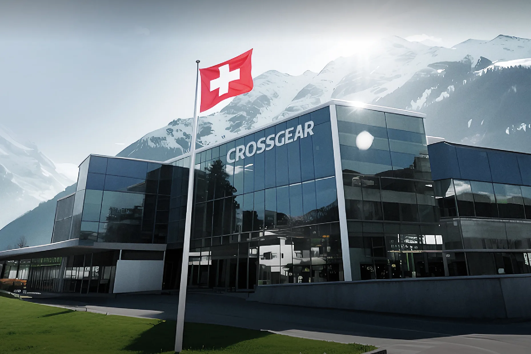 FCSI | A modern glass building labeled "CROSSGEAR" stands in front of snow-capped mountains, with a Swiss flag flying on a pole in the foreground under a bright sky.